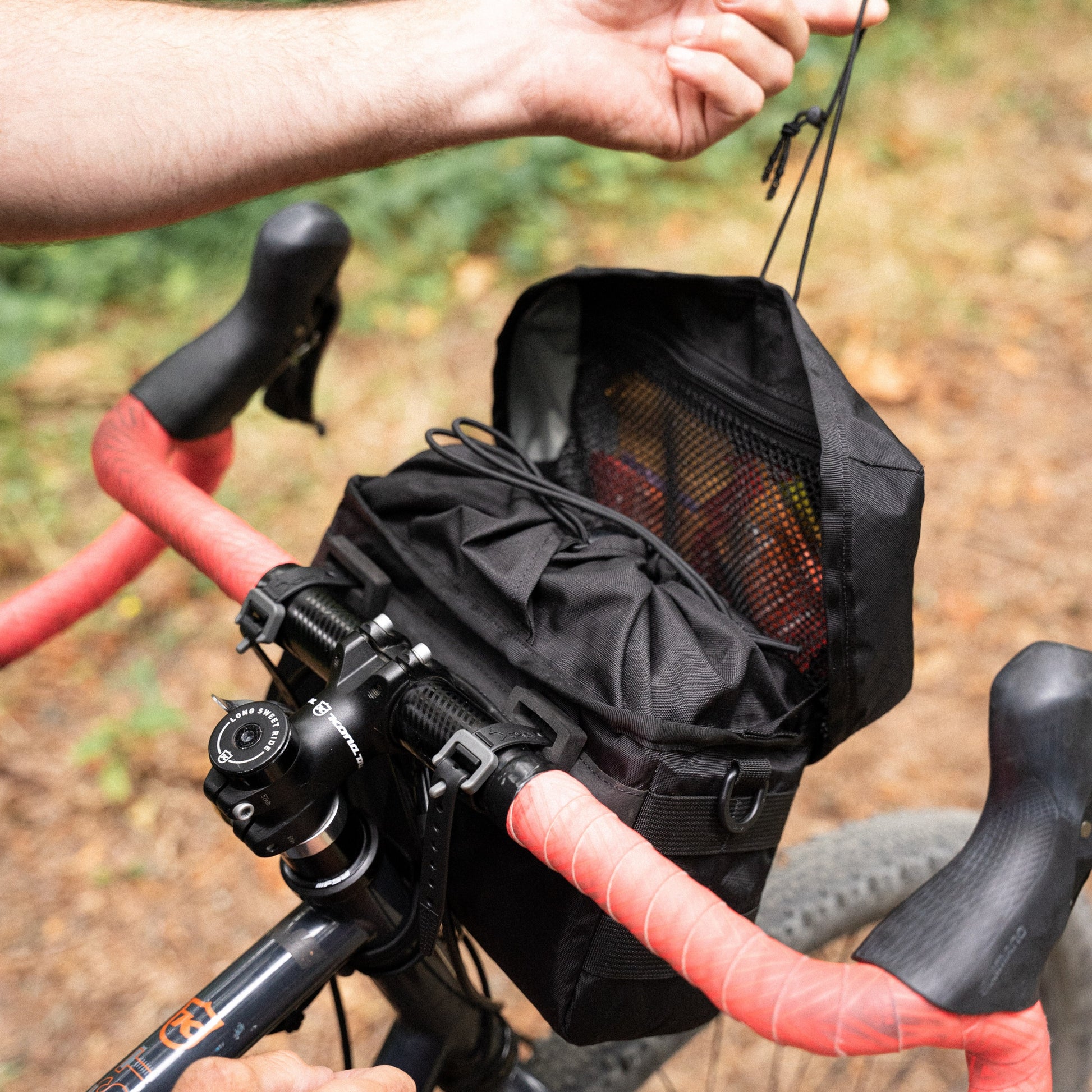 Black bike handlebar bag attached to a bicycle with a natural background