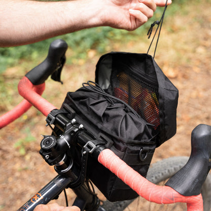 Black bike handlebar bag attached to a bicycle with a natural background